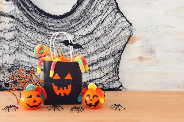 Urlaub Bild von halloween. Kürbisse, Fledermäuse, Leckereien, Papiergeschenktüte über Holztisch — Stockfoto