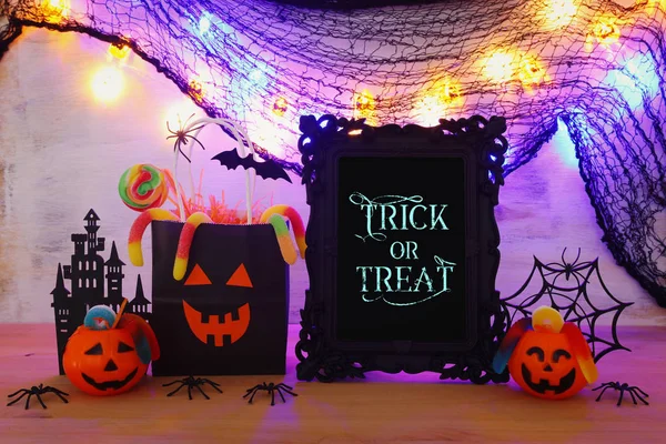 Immagine vacanze di Halloween. Zucche, pipistrelli, dolcetti, sacchetto regalo di carta sul tavolo di legno — Foto Stock