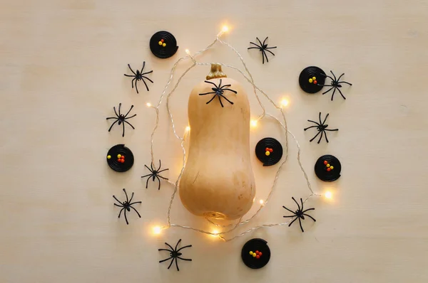 holidays Halloween image. pumpkin and gold garlan lights over wooden white table. top view, flat lay
