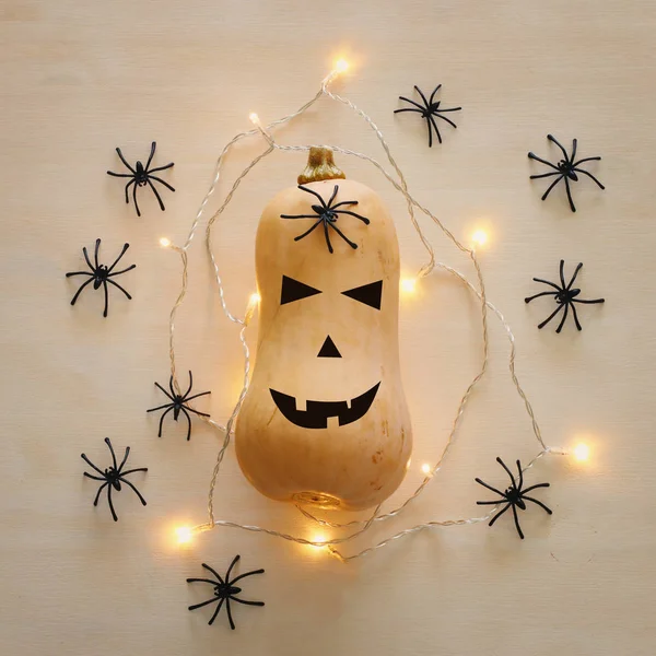 holidays Halloween image. Cute and scary face of pumpkin over wooden white table. top view, flat lay