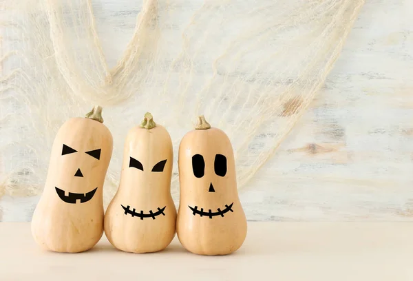 holidays Halloween image. Cute and scary face of pumpkin over wooden white table