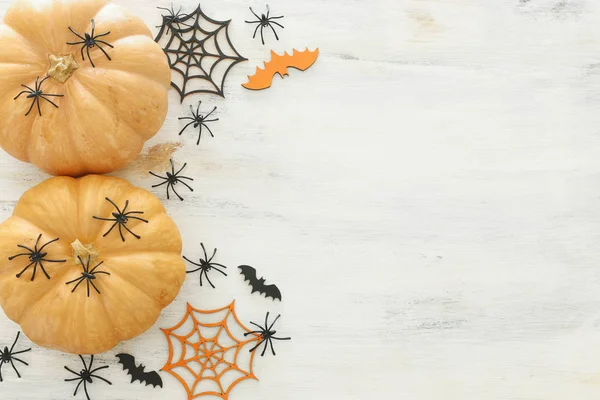 Feiertags-Halloween-Bild. Kürbis, Fledermäuse und Spinnen über einem weißen Holztisch. Draufsicht, flache Lage — Stockfoto