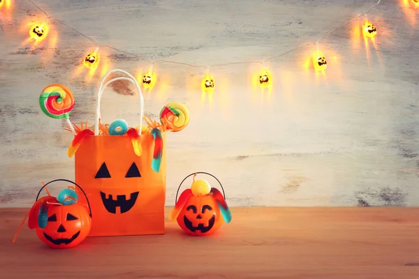 Urlaub Bild von halloween. Kürbisse, Fledermäuse, Leckereien, Papiergeschenktüte über Holztisch — Stockfoto