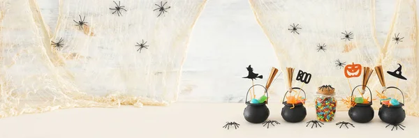 Immagine vacanze di Halloween. Calderone stregone, ginestra, caramelle e ragni sul tavolo di legno bianco — Foto Stock