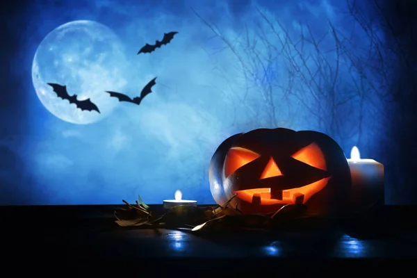 Concepto de vacaciones de Halloween. Calabazas sobre mesa de madera por la noche bosque espeluznante, embrujado y brumoso — Foto de Stock