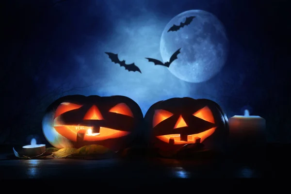 Concetto di festa di Halloween. Zucche sul tavolo di legno di notte foresta spaventosa, infestata e nebbiosa — Foto Stock