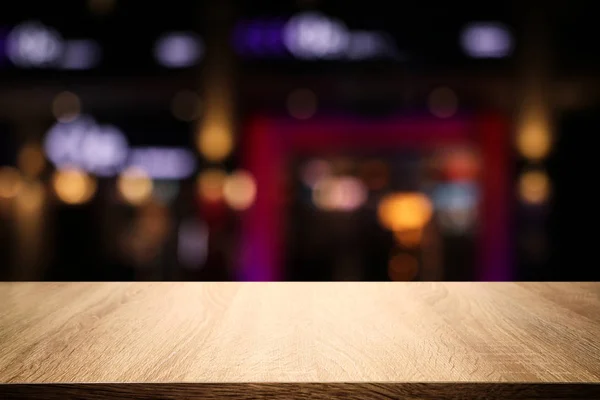 Fondo de la mesa de madera frente a las luces abstractas borrosas del restaurante — Foto de Stock