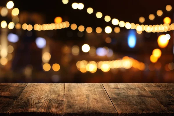 Background of wooden table in front of abstract blurred restaurant lights — Stock Photo, Image