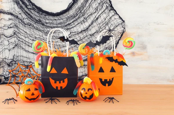 Urlaub Bild von halloween. Kürbisse, Fledermäuse, Leckereien, Papiergeschenktüte über Holztisch — Stockfoto