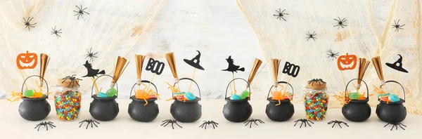Urlaub Bild von halloween. Hexenkessel, Besen, Bonbons und Spinnen über weißem Holztisch — Stockfoto