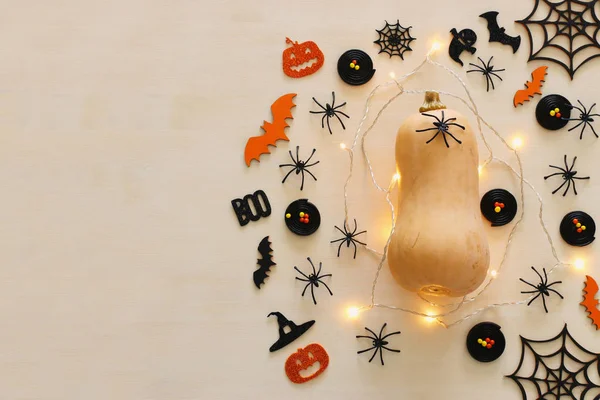 holidays Halloween image. pumpkin and gold garlan lights over wooden white table. top view, flat lay