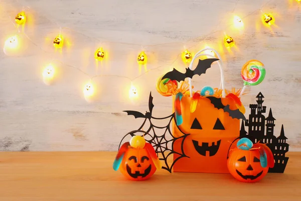 Urlaub Bild von halloween. Kürbisse, Fledermäuse, Leckereien, Papiergeschenktüte über Holztisch — Stockfoto