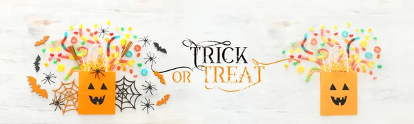 Ünnepek kép Halloween. papír ajándékcsomagot, pók, denevérek és édességek felett fából készült fehér asztal. felülnézet, lapos Lay — Stock Fotó