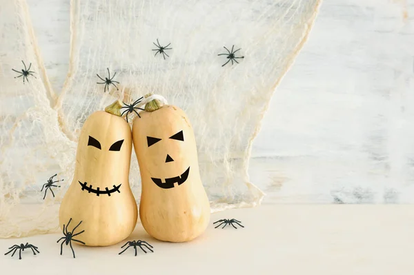 holidays Halloween image. Cute and scary face of pumpkin over wooden white table