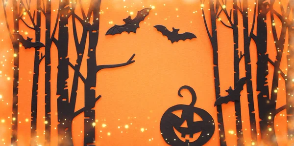 Concepto de vacaciones de Halloween. Bosque embrujado, calabaza y murciélagos negros sobre fondo naranja. Vista superior, plano —  Fotos de Stock
