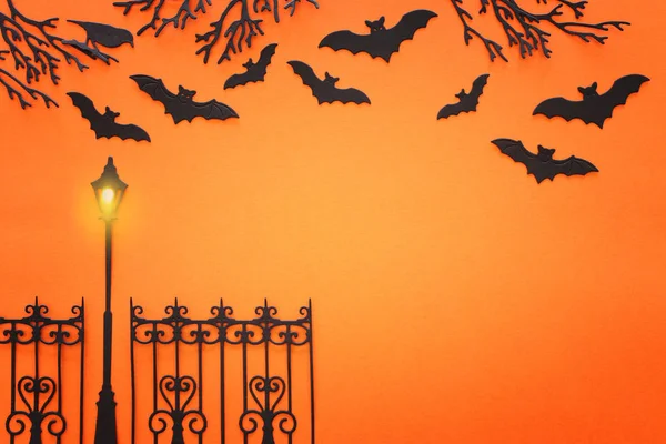 Feiertags-Halloween-Konzept. gespenstische Allee mit Bäumen und Fledermäusen vor orangefarbenem Hintergrund. Draufsicht, flache Lage — Stockfoto