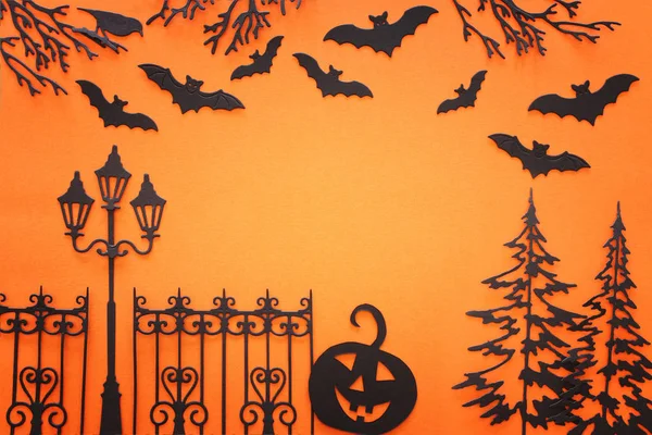 Feiertags-Halloween-Konzept. gespenstische Allee mit Bäumen und Fledermäusen vor orangefarbenem Hintergrund. Draufsicht, flache Lage — Stockfoto