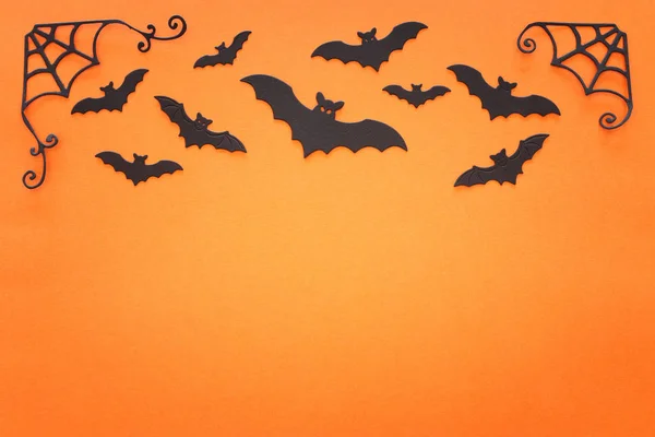 Feestdagen concept van Halloween. Zwarte vleermuizen over oranje achtergrond. Bovenaanzicht, vlak lay — Stockfoto