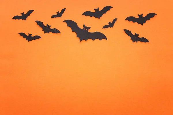 Semester begreppet Halloween. Svarta fladdermöss över orange bakgrund. Ovanifrån, platt ligg — Stockfoto