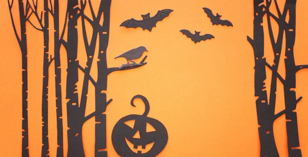 Concepto de vacaciones de Halloween. Bosque embrujado, calabaza y murciélagos negros sobre fondo naranja. Vista superior, plano —  Fotos de Stock