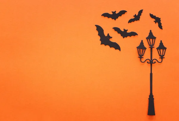 Dovolená Halloween koncept. vintage pouliční lampa a netopýři přes oranžové pozadí. Pohled shora, byt ležel — Stock fotografie