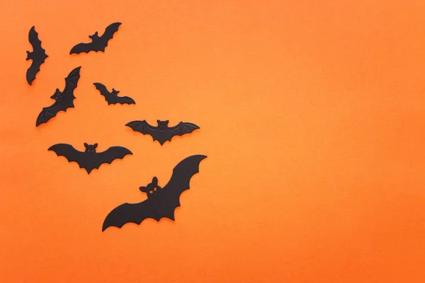 Feestdagen concept van Halloween. Zwarte vleermuizen over oranje achtergrond. Bovenaanzicht, vlak lay — Stockfoto