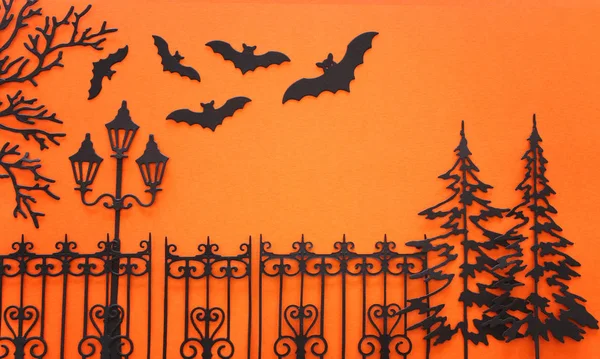 Koncepcja święta Halloween. nawiedzona aleja z zabytkowym ogrodzeniem, uliczne drzewa lampy i nietoperze na pomarańczowym tle. Widok z góry, płaski — Zdjęcie stockowe
