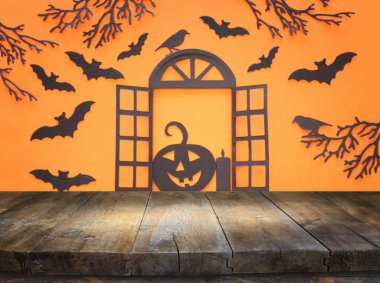 holidays concept of Halloween. Empty rustic table in front of open window and bats over orangr background. Ready for product display montage