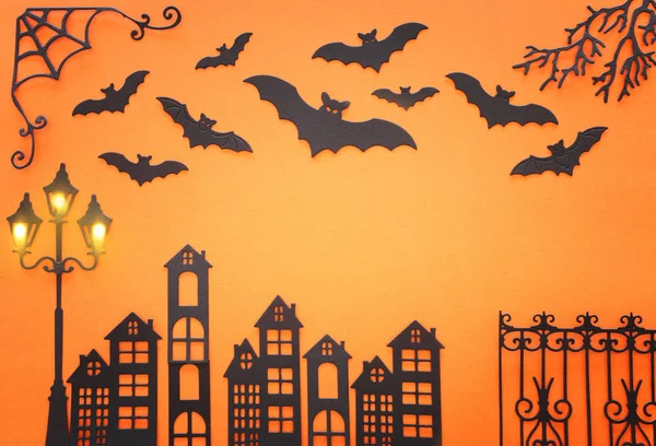 Vacanze concetto di Halloween. vicolo infestato con recinzione d'epoca, alberi lampione e pipistrelli su sfondo arancione. Vista dall'alto, piatta — Foto Stock