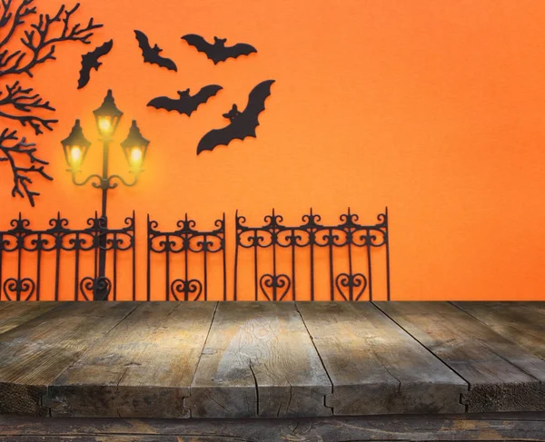 Concetto di festa di Halloween. Tavolo rustico vuoto di fronte a vicolo infestato e pipistrelli su sfondo arancione. Montaggio pronto per l'esposizione del prodotto — Foto Stock