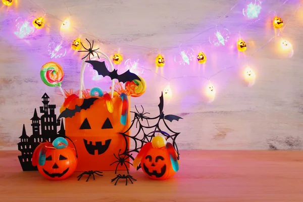 Праздничный образ Хэллоуина. Тыквы, летучие мыши, лакомства, бумажный подарочный пакет на деревянный стол — стоковое фото
