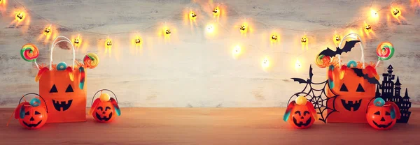 Urlaub Bild von halloween. Kürbisse, Fledermäuse, Leckereien, Papiergeschenktüte über Holztisch — Stockfoto