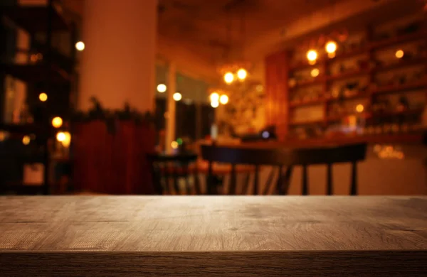 Hintergrund Bild eines Holztisches vor abstrakten verschwommenen Restaurantlichtern — Stockfoto