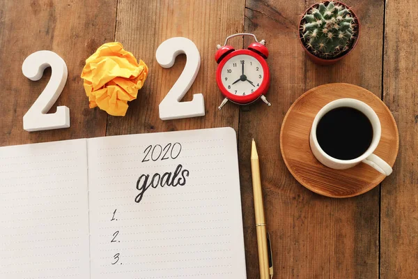 Business concept of top view 2020 goals list with notebook, cup of coffee over wooden desk — Stock Photo, Image
