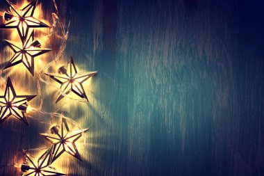 Noel tatili kavramı sıcak altın çelenk ışıkları ahşap mavi arka planda