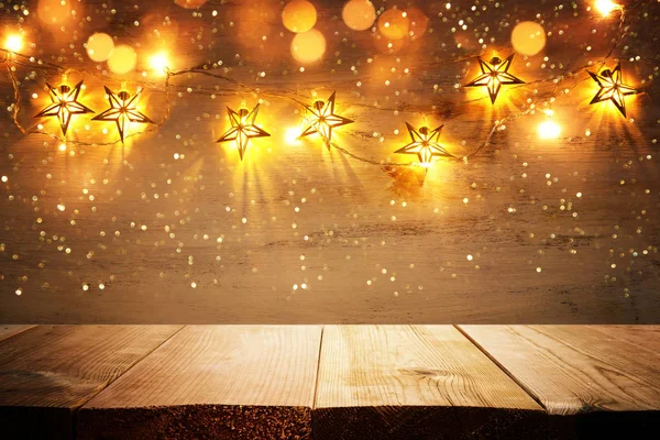 Background image of wooden board table in front of Christmas warm gold garland lights. filtered image. selective focus. glitter overlay — Stock Photo, Image