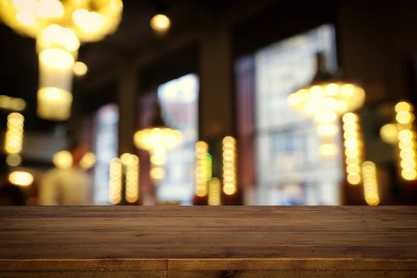 在抽象模糊的餐厅灯光前的木制桌子图像 — 图库照片