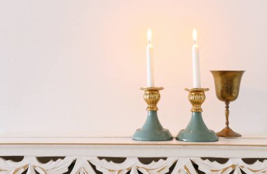 Ahşap masanın üzerinde yanan mumlarla iki şabat şamdanı.