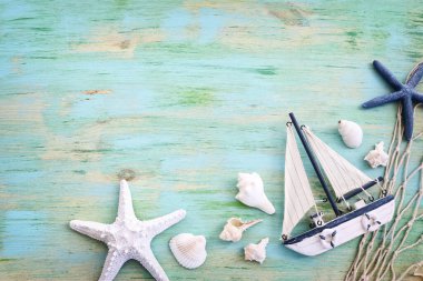 Beyaz dekoratif yelkenli tekne, mavi ahşap arka planda deniz kabukları