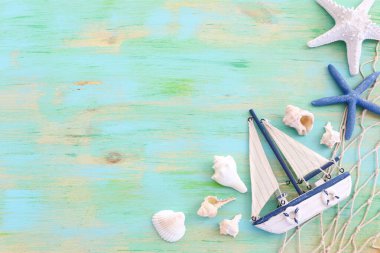 Beyaz dekoratif yelkenli tekne, mavi ahşap arka planda deniz kabukları