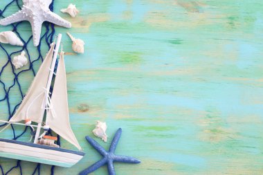 Beyaz dekoratif yelkenli tekne, mavi ahşap arka planda deniz kabukları