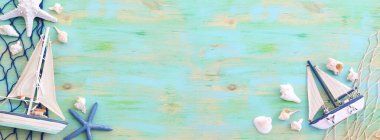 Beyaz dekoratif yelkenli tekne, mavi ahşap arka planda deniz kabukları