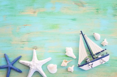 Beyaz dekoratif yelkenli tekne, mavi ahşap arka planda deniz kabukları