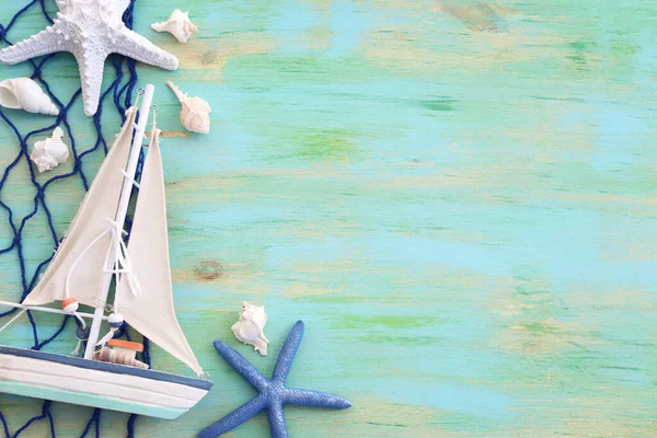 白い装飾の帆のボート 青い木製の背景の上の貝殻と航海の概念 — ストック写真