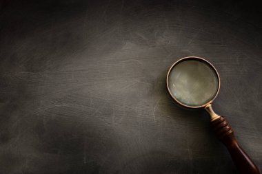 Tahta arka planda tahta saplı klasik büyüteç. Üst görünüm, düz uzanma