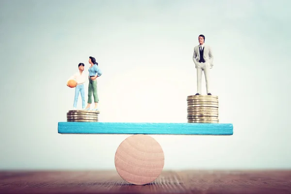 Conceptual image of gender inequality. A woman and a man on either side of the scales, with income difference