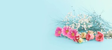 Pastel mavi arka planda pembe ve beyaz çiçeklerden oluşan bir buket