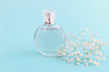 Mavi pastel arka planda zarif bir parfüm şişesi resmi