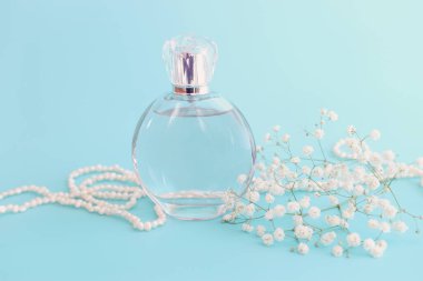 Mavi pastel arka planda zarif bir parfüm şişesi resmi