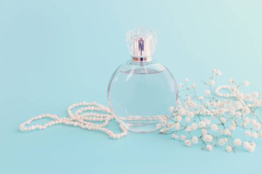 Mavi pastel arka planda zarif bir parfüm şişesi resmi